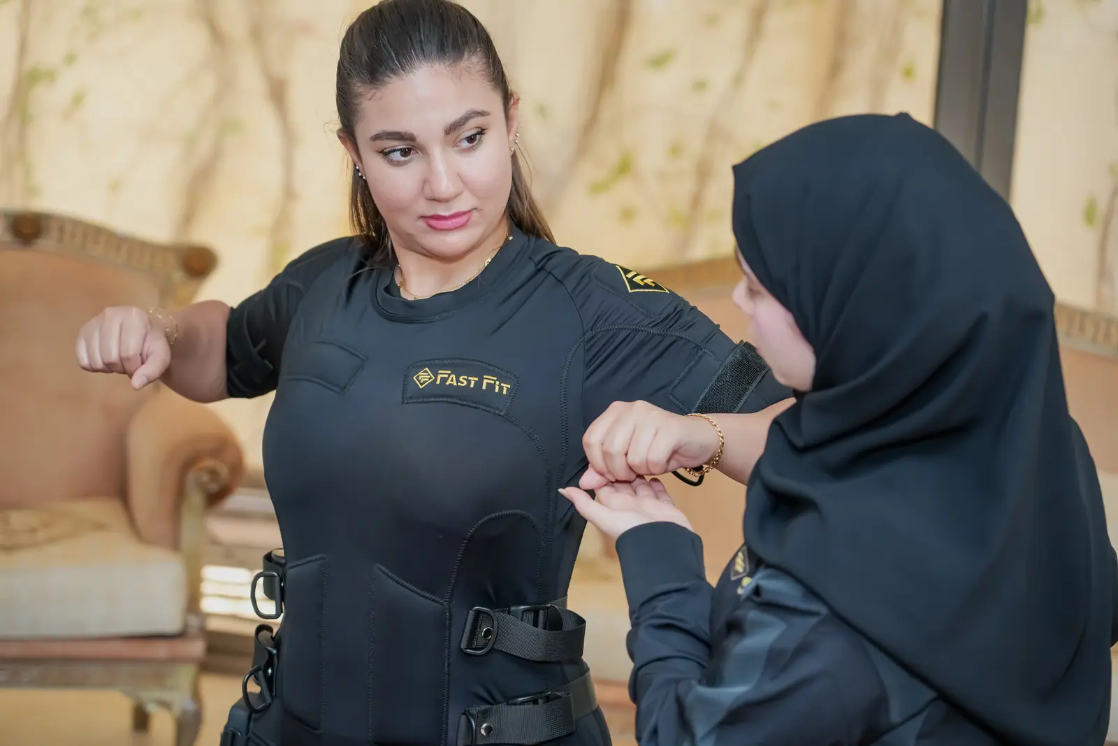 Female trainer guiding a client through an EMS session at home